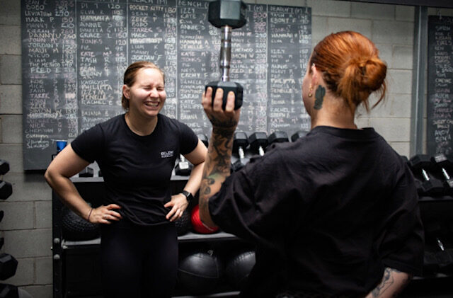 Hannah coaching a client through a dumbbell press