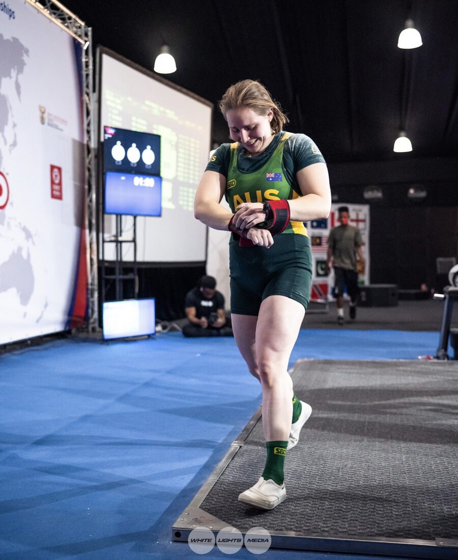 Hannah in the green-and-gold, walking off the platform at an international meet