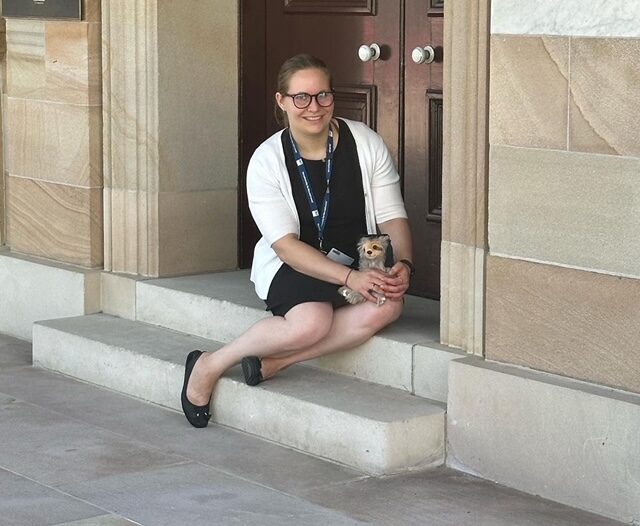 Hannah seated on sandstone steps in university dress